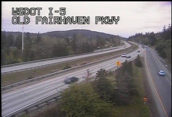 A WSDOT traffic camera frame labelled I-5 OLD FAIRHAVEN PKWY: the interstate curving away between wooded hills, a few cars, nobody on the shoulder.